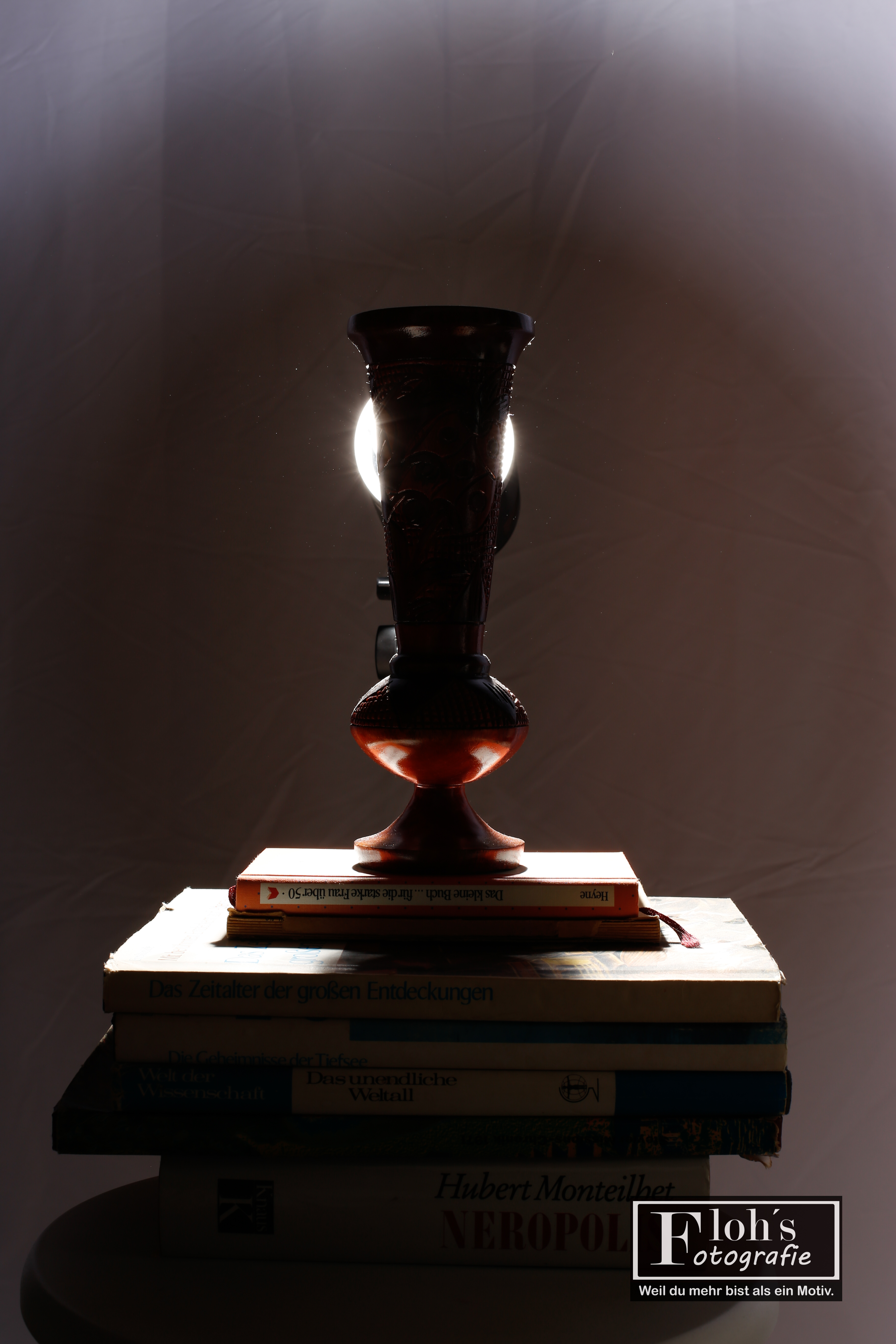 Thema Punkt – Vase auf Büchern im Rampenlicht beim Wiener Fotomarathon 2025