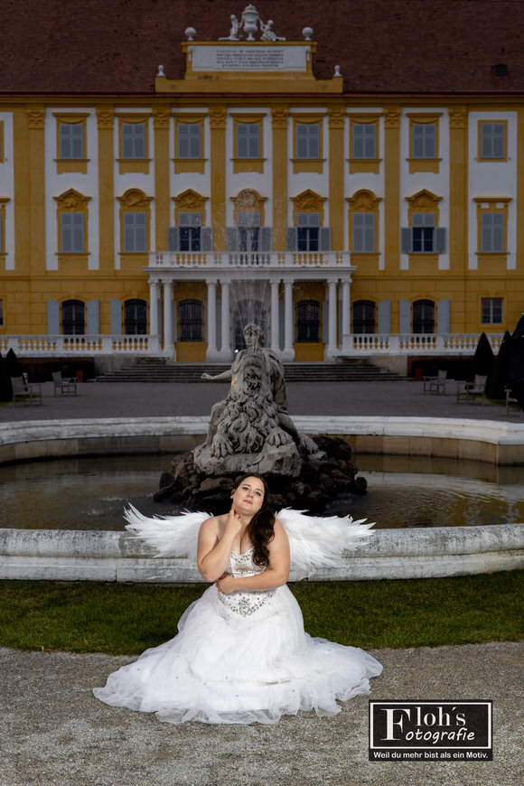 Engel-Cosplay von Vici vor rot beleuchtetem Höhleneingang, mystische Stimmung.