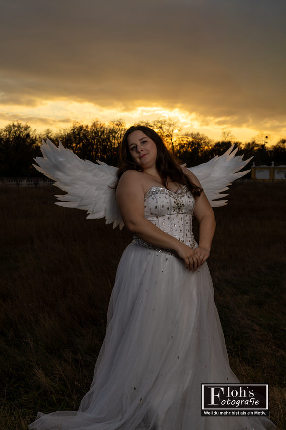 Himmlisches Engel-Cosplay vor dem Brunnen von Burg Hof, Vici in ruhiger Pose.