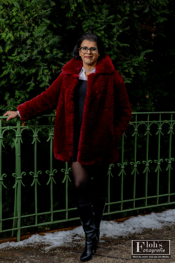 1️⃣ Portrait Shooting Wien mit Arya im Stadtpark, stehend am grünen Geländer mit rotem Mantel im Winter.