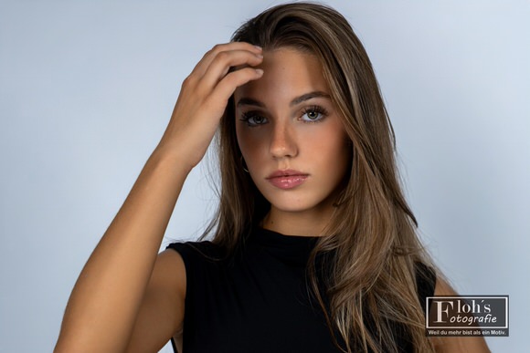 Nahaufnahme von Christina mit einer Hand am Haaransatz, offenem Haar und direktem Blick in die Kamera.