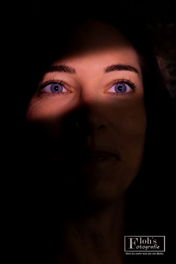 Portrait von Lisa mit nach oben gerichtetem Blick und warmem Licht über den Augen, während der untere Teil ihres Gesichts im Schatten liegt.
