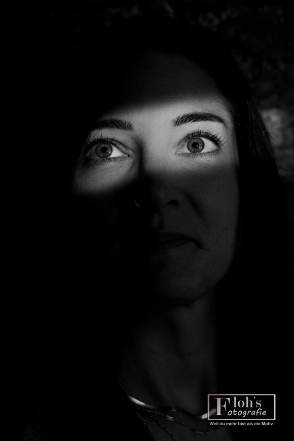 Schwarz-Weiß-Portrait von Lisa mit nach oben gerichtetem Blick, hell beleuchteten Augen und starken Schatten über Nase und Mund.